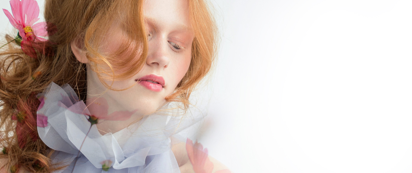 beautiful redhead girl with soft pink spring makeup framed by flowers